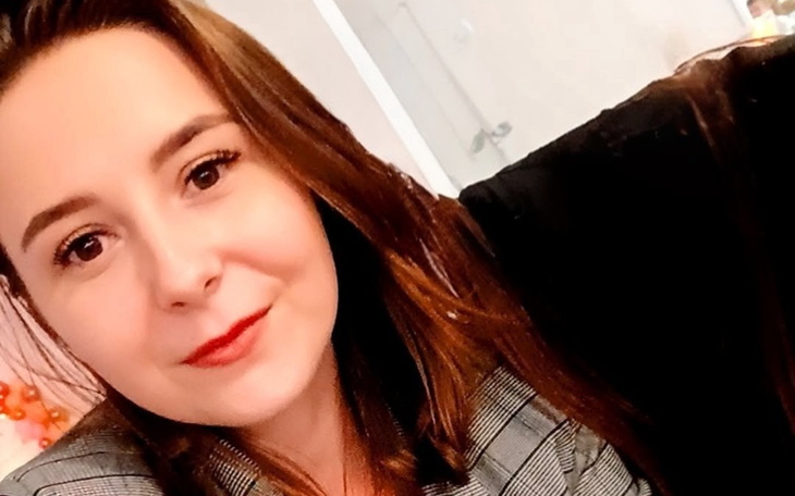 Portret młodej kobiety w eleganckim ubraniu, uśmiechającej się do kamery.