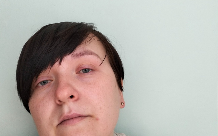 Kobieta z krótkimi włosami, patrzy w obiektyw.