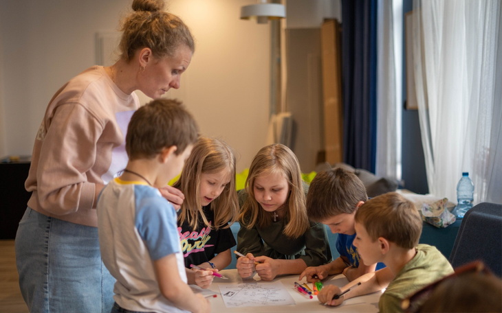 Dzieci rysują z nauczycielem w przytulnym wnętrzu.