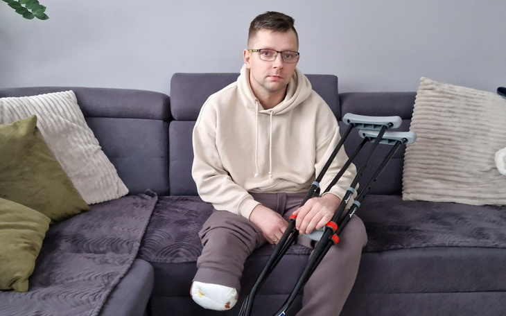 Mężczyzna siedzi na kanapie z kulami, wygląda na zamyślonego.