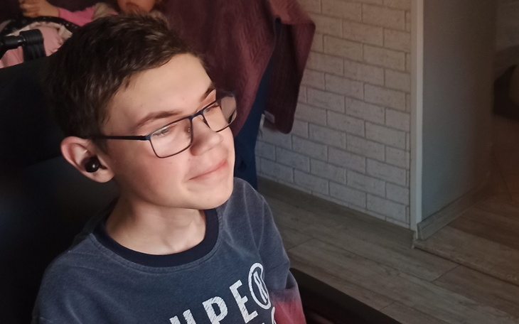 Chłopiec w okularach, uśmiechający się do kamery.