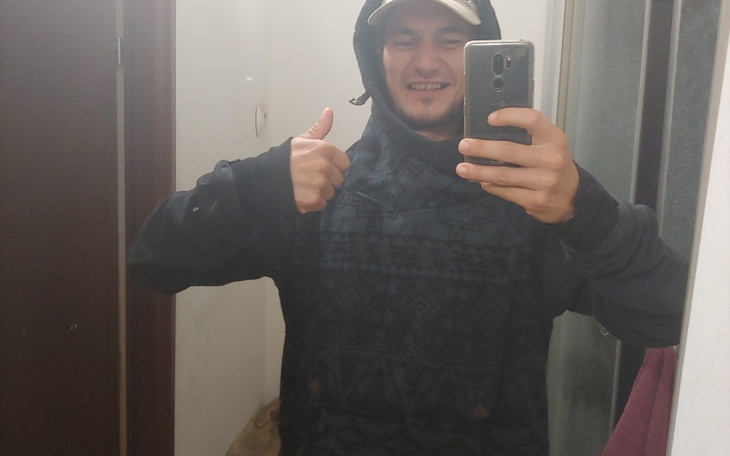 Mężczyzna w czarnej bluzie, uśmiechający się i pokazujący kciuk w górę.