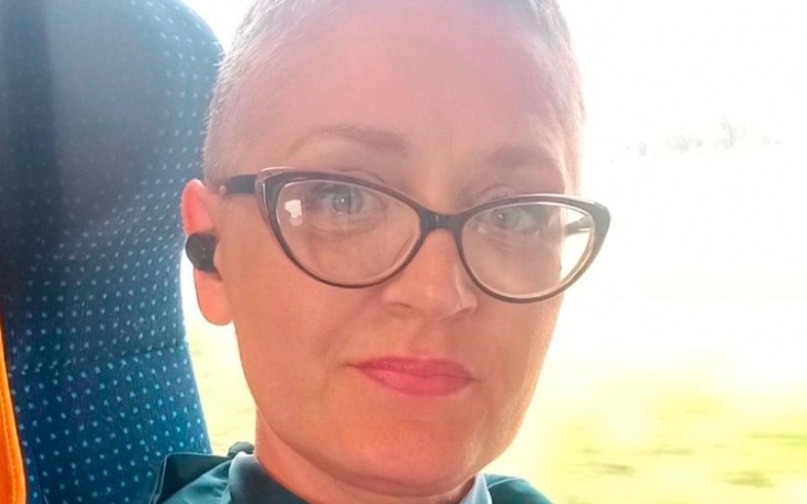 Kobieta w okularach na tle okna w autobusie.