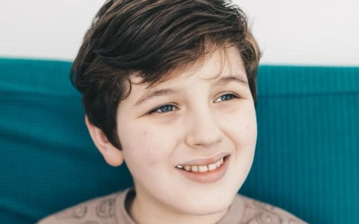 Chłopiec z uśmiechem, siedzący na kanapie.