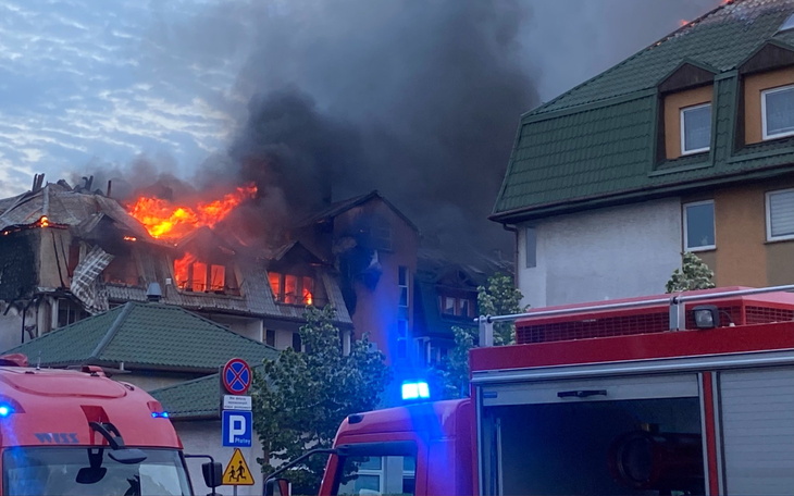 Pożar w budynku mieszkalnym, z widocznymi płomieniami i dymem.