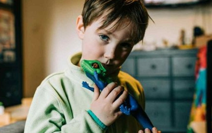 Chłopiec przytulający zabawkę w kształcie jaszczurki.