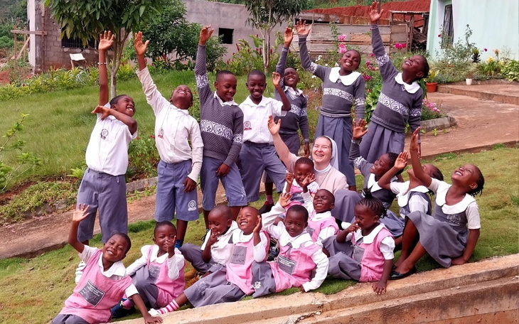 Grupa dzieci z radością pozująca do zdjęcia z siostrą.