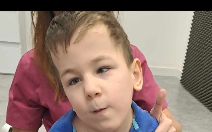 Chłopiec z krótkimi włosami, uśmiechający się do kamery.