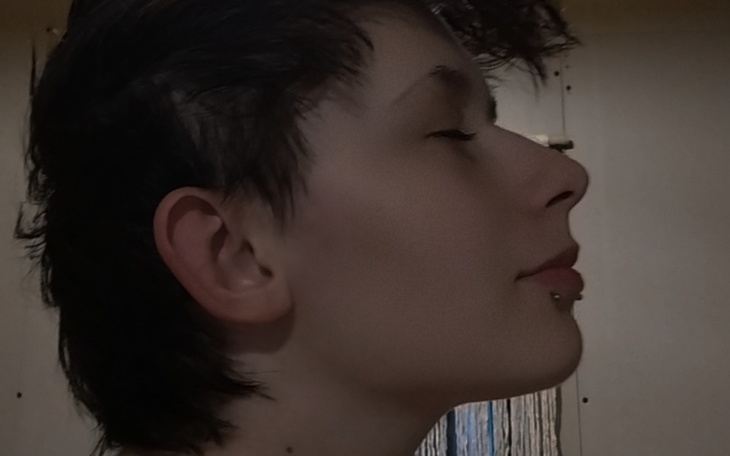 Profil młodej osoby z krótkimi włosami i kolczykiem.