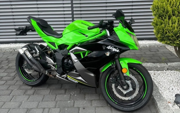 Zielony motocykl sportowy na tle nowoczesnej architektury.