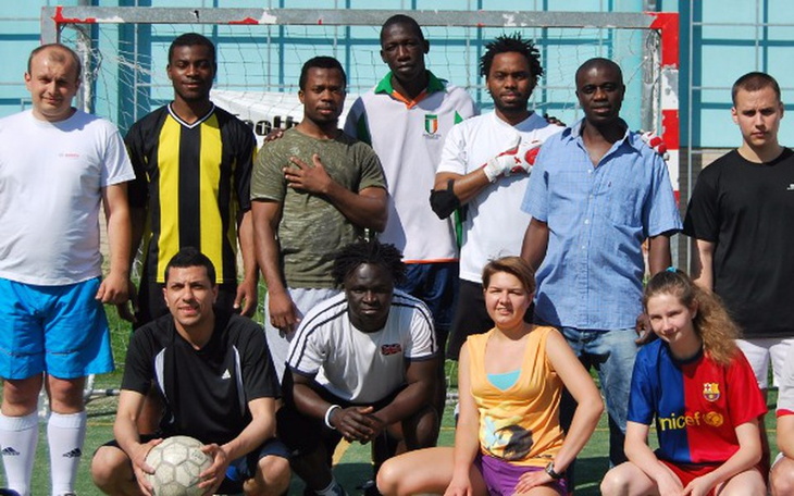 Grupa ludzi pozująca do zdjęcia na boisku piłkarskim.