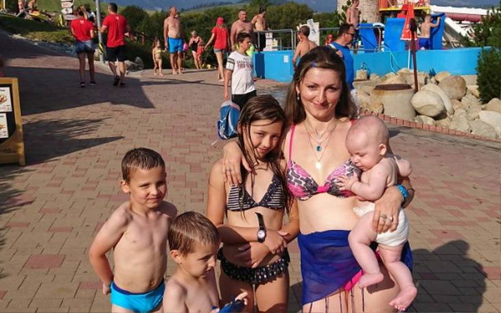 Rodzina na wakacjach, dzieci w strojach kąpielowych przy basenie.