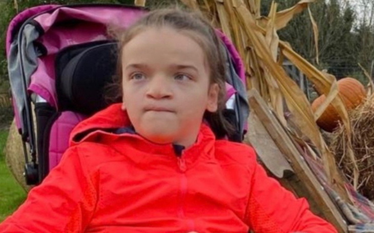 Dziewczynka w wózku na tle kukurydzy, w czerwonej kurtce.