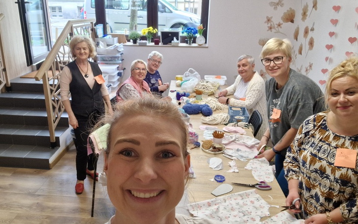 Grupa kobiet pracujących nad projektami rękodzielniczymi w przytulnym wnętrzu.