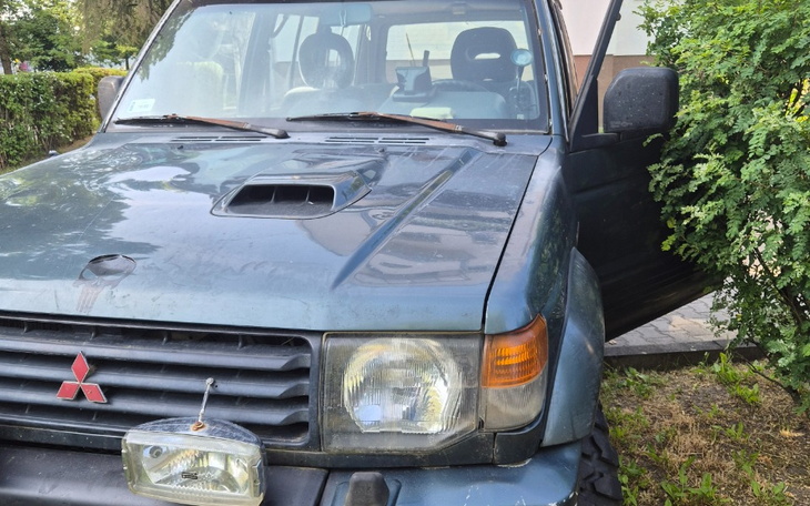 Stary samochód zaparkowany przy ogrodzeniu.