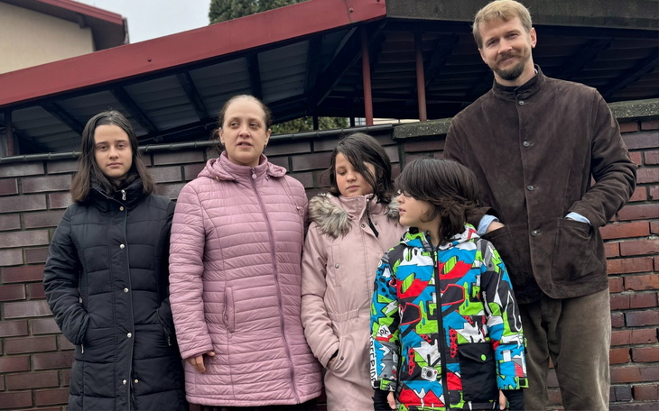 Rodzina pozująca na tle ogrodzenia.