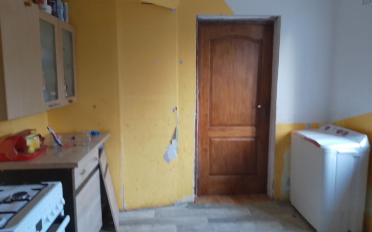 Widok na kuchnię z żółtymi ścianami i drewnianymi drzwiami.