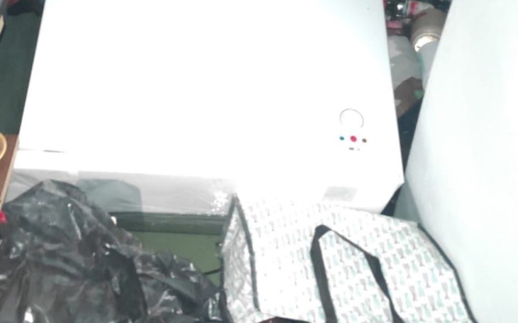 Zamknięta lodówka w zagraconym pomieszczeniu, otoczenie pełne bałaganu.