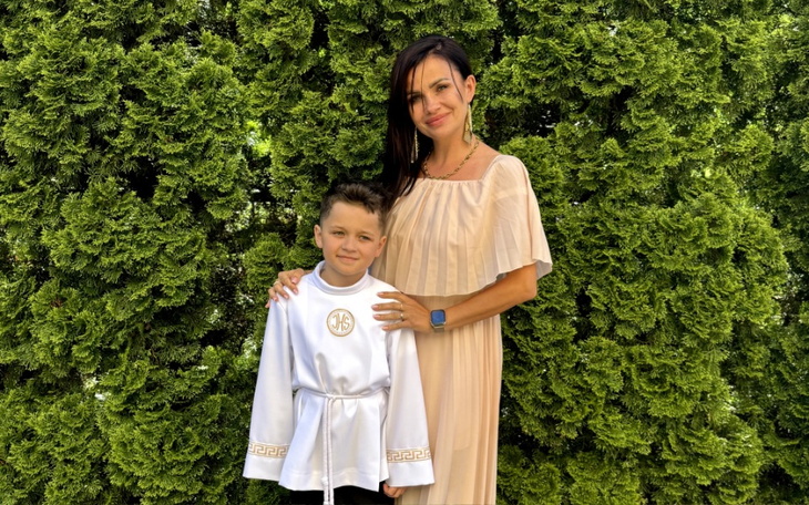 Matka z synem w eleganckich strojach na tle zieleni.