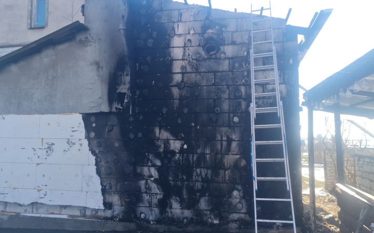 Zniszczona ściana budynku po pożarze, widoczna drabina.