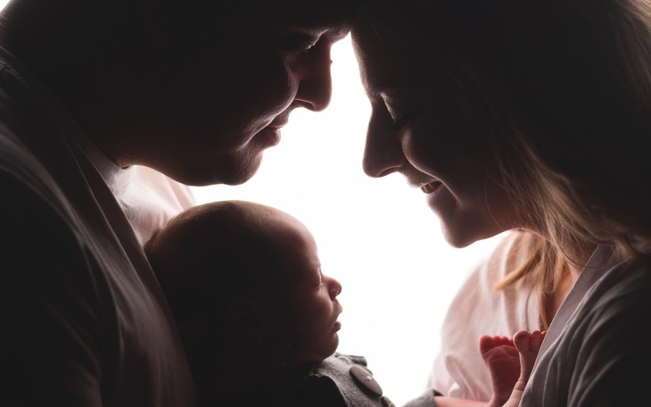 Rodzina w ciepłym ujęciu, trzymająca noworodka.