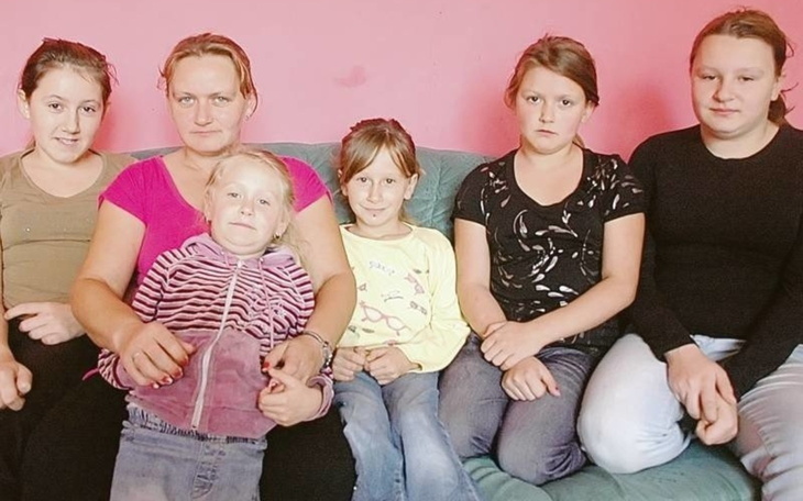 Rodzina kobiet i dziewczynek siedzących na kanapie w salonie.