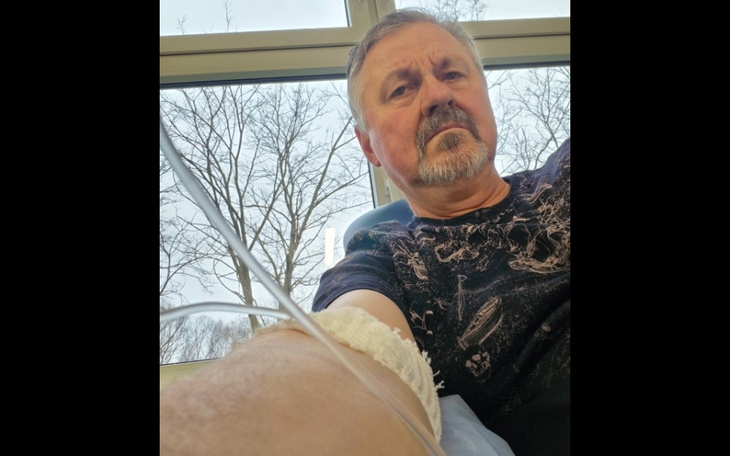 Mężczyzna w szpitalu, z kroplówką i smutnym wyrazem twarzy.