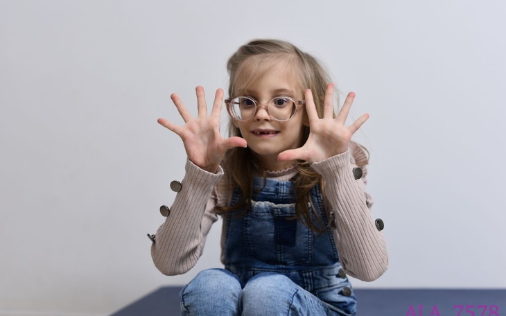 Dziewczynka z okularami, pokazująca ręce w geście radości.