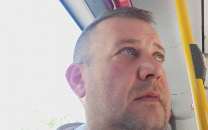Mężczyzna w autobusie, z zamyślonym wyrazem twarzy.
