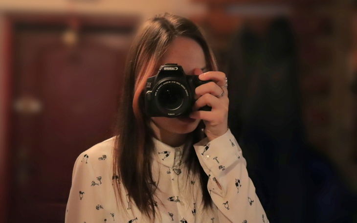 Osoba trzymająca aparat fotograficzny, gotowa do zrobienia zdjęcia.