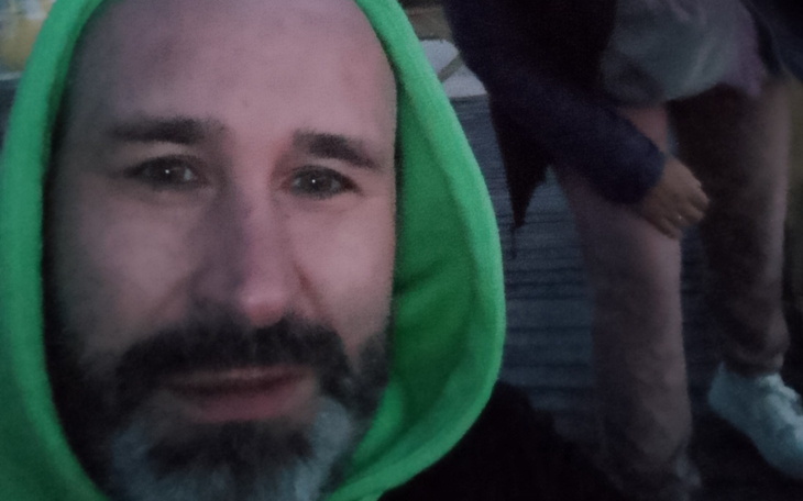 Mężczyzna w zielonym kapturze, selfie na tle molo.