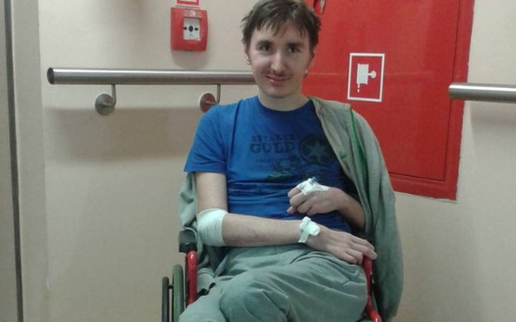 Mężczyzna w wózku inwalidzkim, uśmiechnięty.