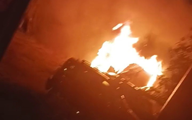 Pojazd w płomieniach, otoczony dymem i ogniem, w dramatycznej scenerii.