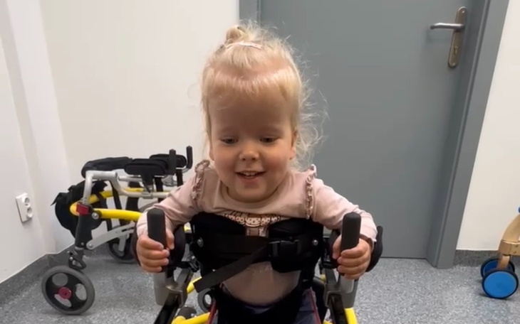 Mała dziewczynka w wózku, uśmiechająca się do kamery.