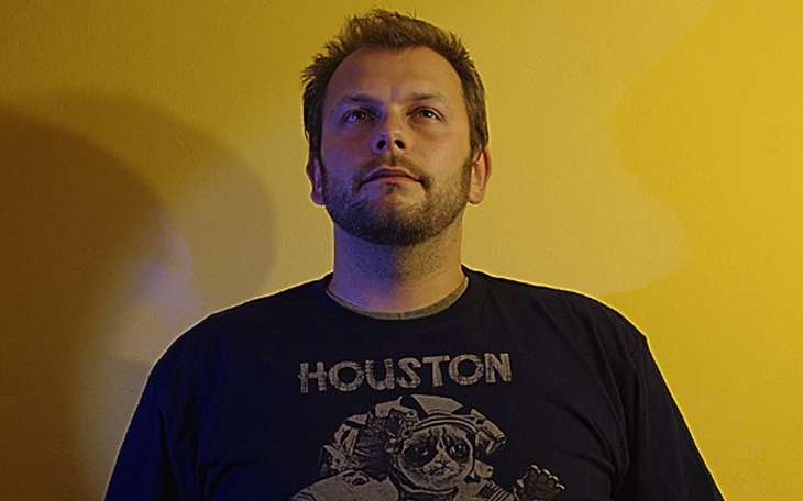 Mężczyzna w koszulce z nadrukiem, patrzący w stronę obiektywu.