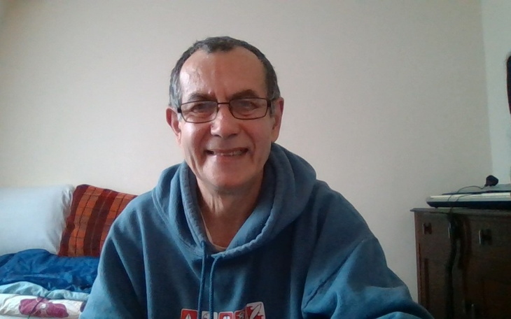 Mężczyzna w okularach, uśmiecha się do kamery.