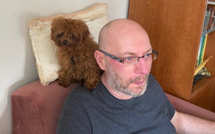 Mężczyzna z psem na kanapie, relaksujący się w domu.