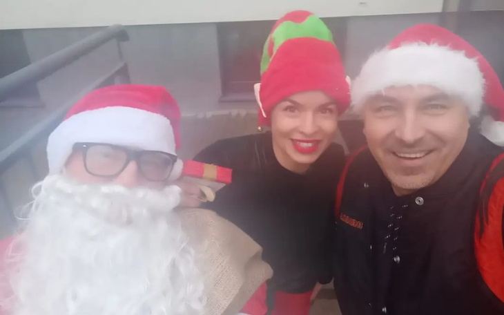 Trzej ludzie przebrani za Świętego Mikołaja i elfy.