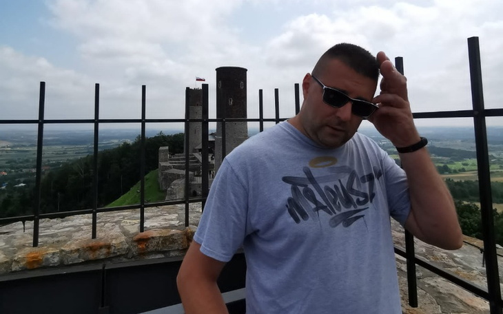 Mężczyzna w okularach przeciwsłonecznych na tle zamku.