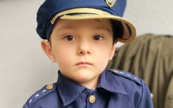 Mały chłopiec w mundurze policjanta, poważnie patrzy w obiektyw.