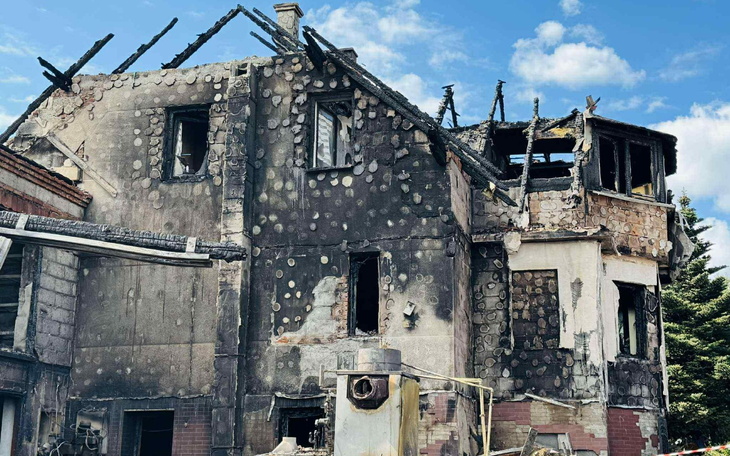 Zniszczony budynek po pożarze, z uszkodzoną konstrukcją dachu.