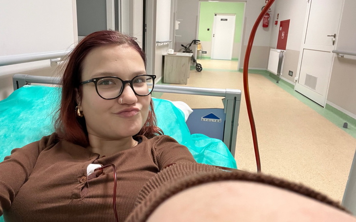 Kobieta w szpitalu, leżąca na łóżku z zielonymi prześcieradłami.