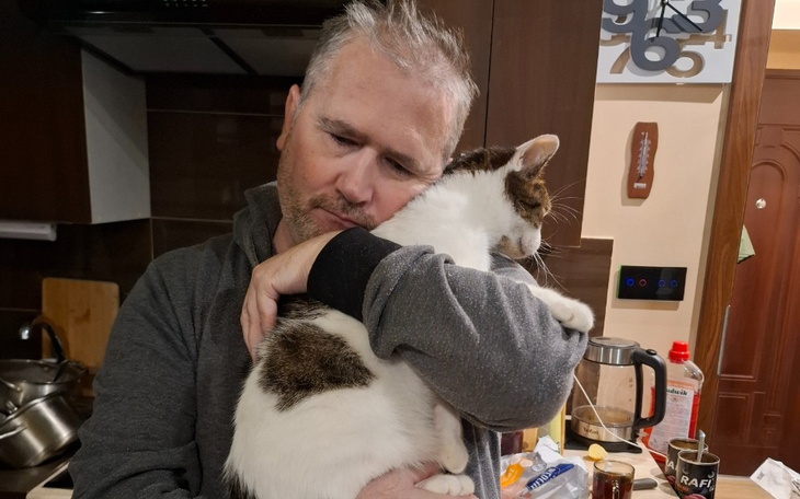 Kot siedzący na tle białej ściany.