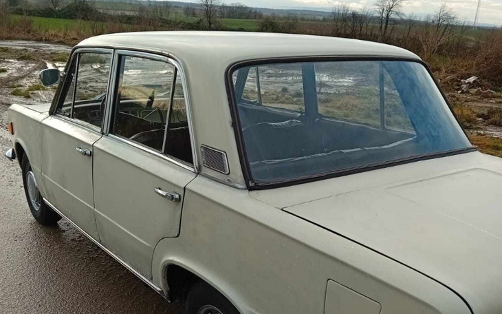 Stary samochód zaparkowany na drodze w otoczeniu natury.