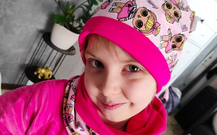 Dziewczynka w różowej czapce z postaciami z bajek.