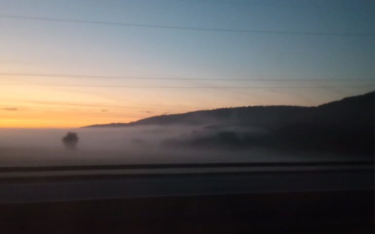 Poranny widok na mglistą dolinę, słońce wschodzi nad horyzontem.