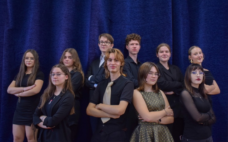 Grupa młodych ludzi pozująca do zdjęcia w eleganckich strojach.