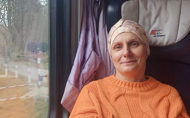 Kobieta w pomarańczowym swetrze, podróżująca pociągiem.