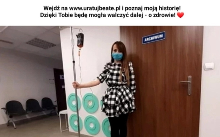 Kobieta w sukience w kratę, trzymająca kroplówkę w szpitalu.