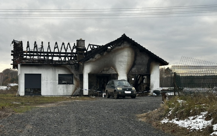 Zniszczony dom po pożarze, z samochodem przed budynkiem.